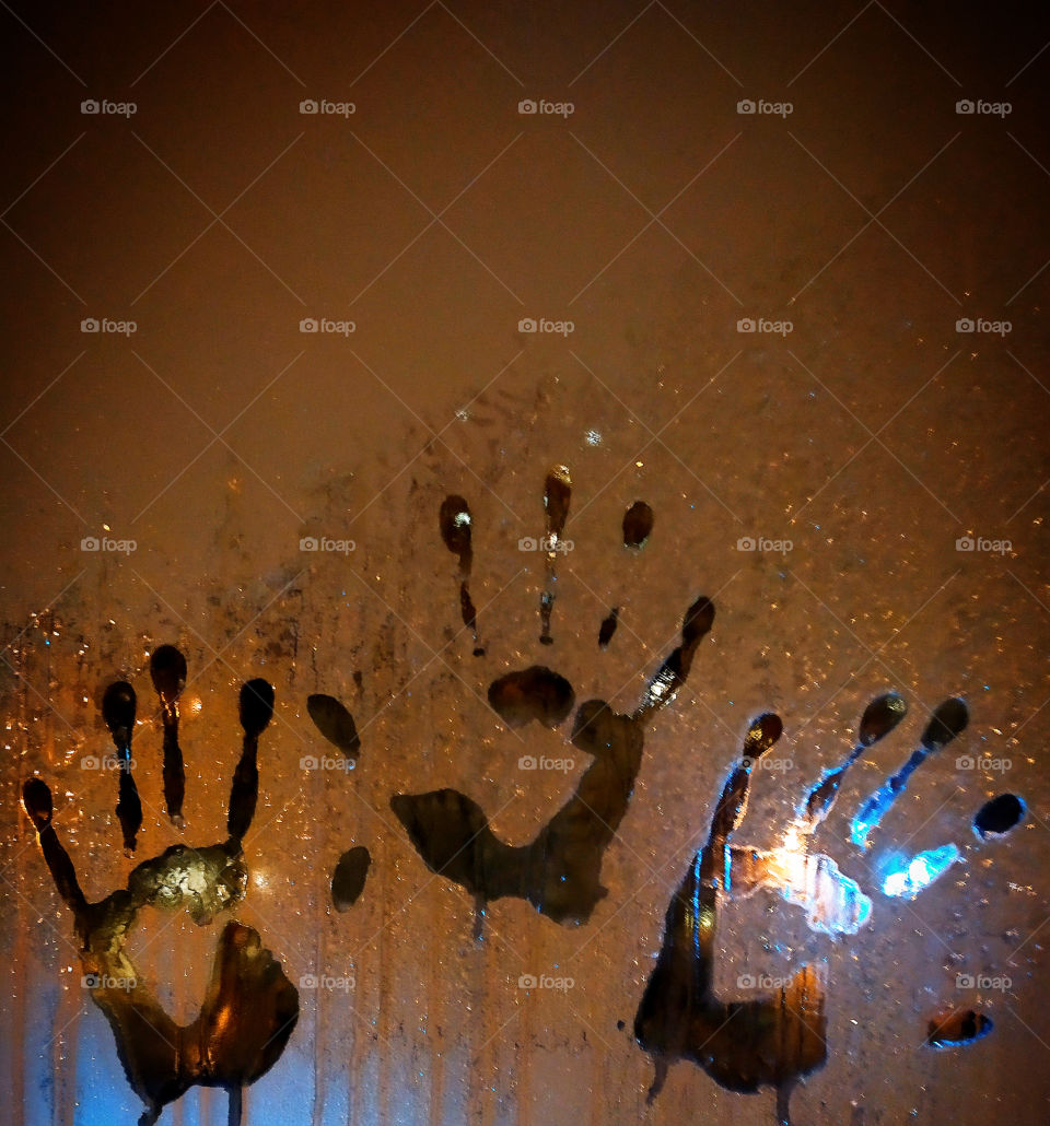 Three palm prints on frozen glass