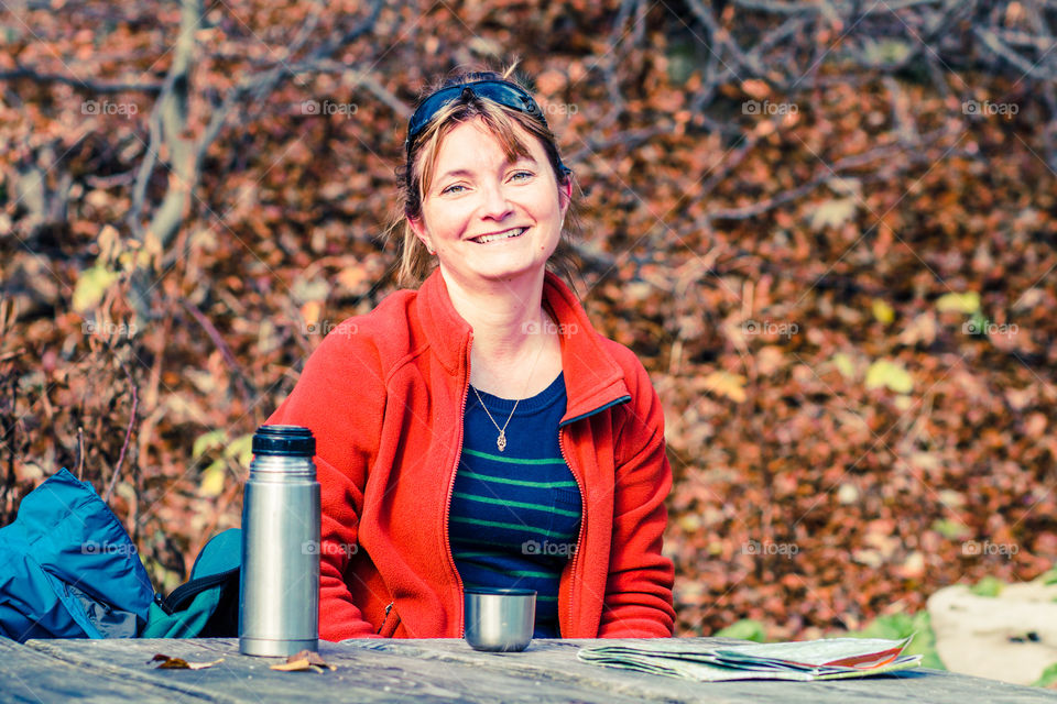 Woman resting during hiking in Bieszczady Mountains, drinking hot tea from thermos bottle