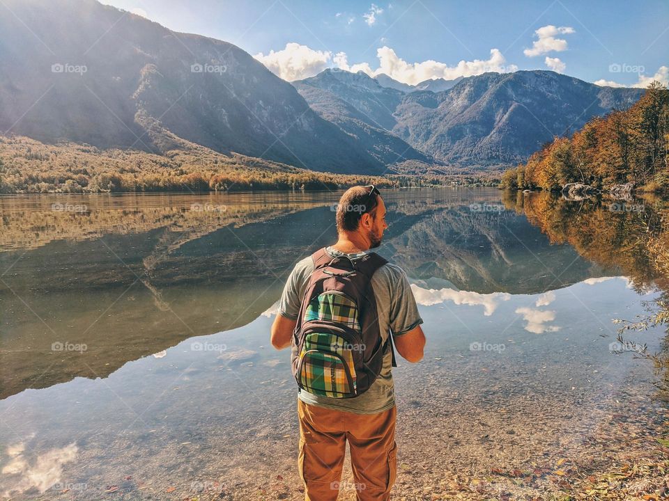 portrait of young happy man in Alps mountains and blue lake in Slovenia.  autumn Time