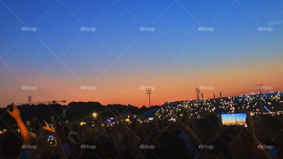 Open air concert, phone lights during sunset
