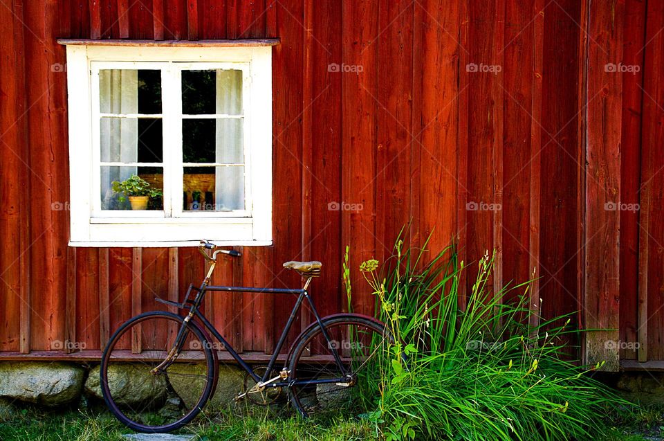 Vintage bike is leaning at a red, wooden wall