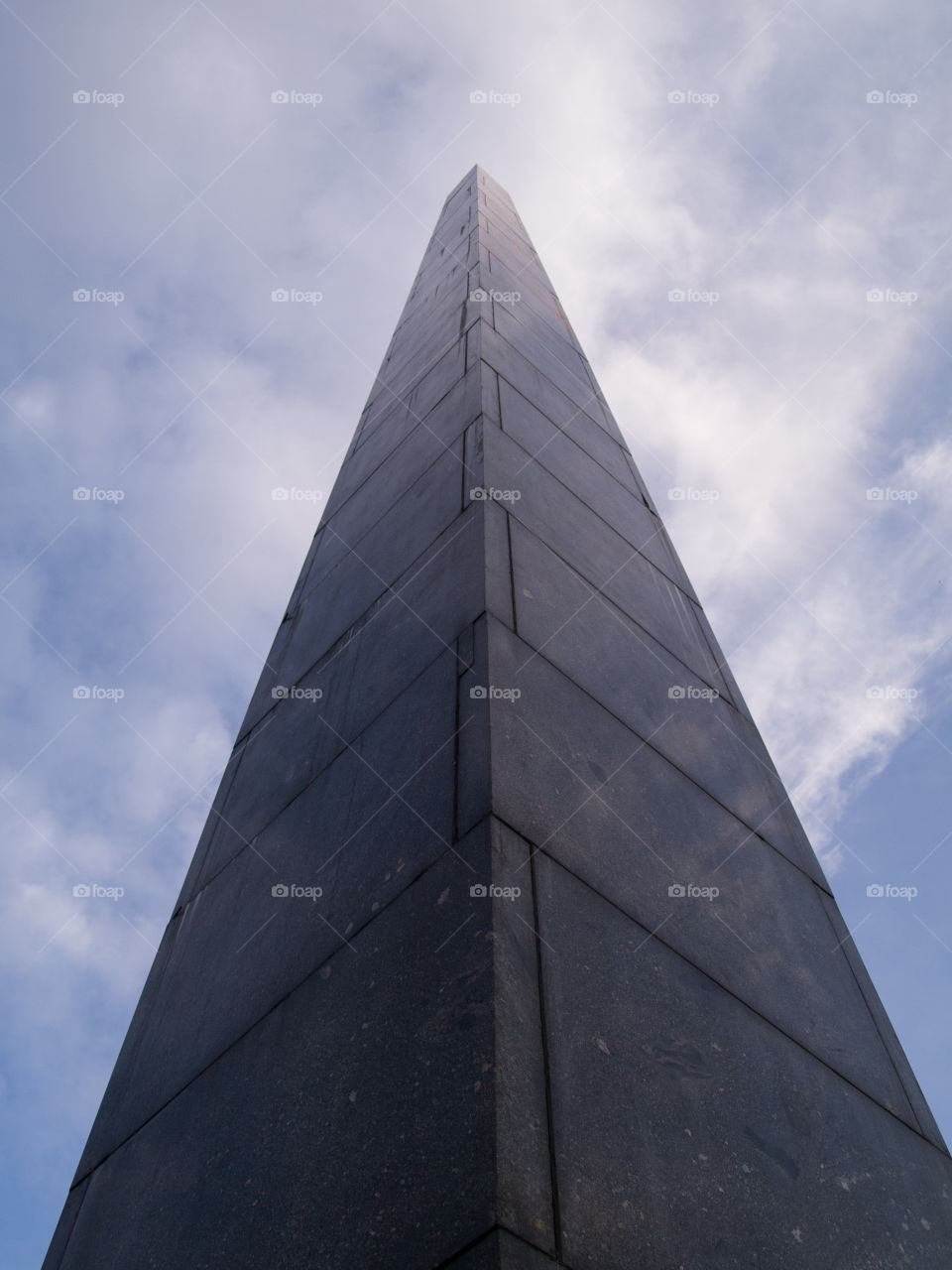 gray concrete cone-shaped monument under a blue sky with white clouds