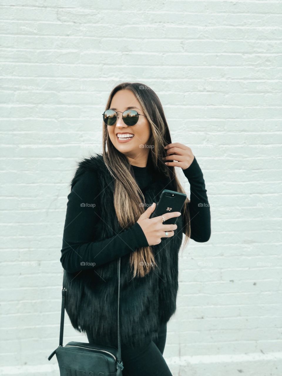 Fashionable girl wearing a black fur coat against a  bright white wall.