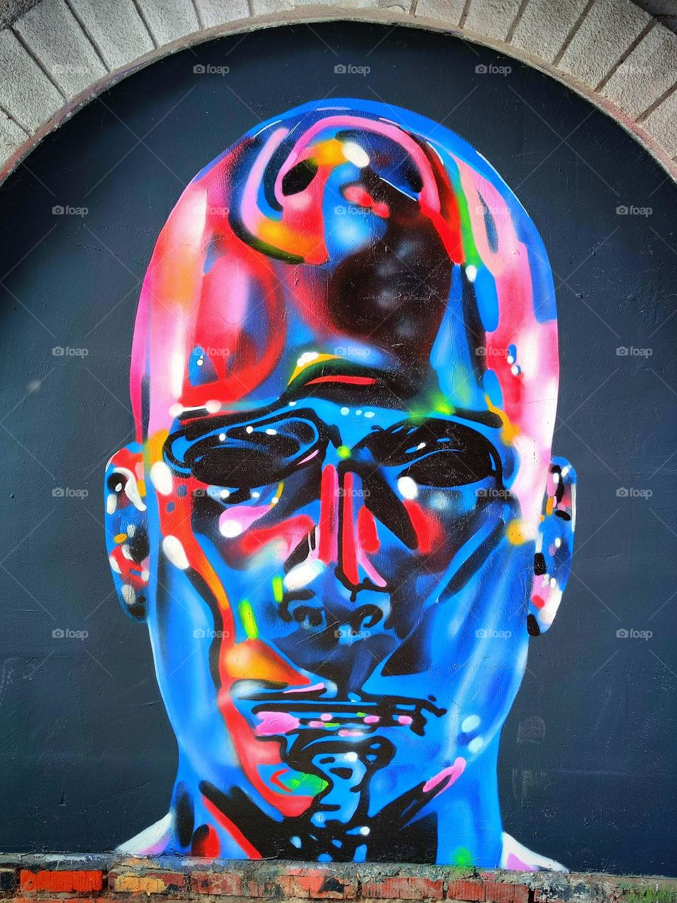 Street art. Graffiti. The head of a man is depicted on the wall. Multicolored paint colors perfectly contrast with each other. Unusual color find