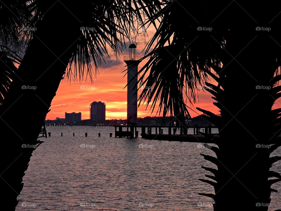 
Magic of Sunrise and Sunset - The big orange and gold descending sunset slowly going down and down behind the lighthouse as it sets into the horizon