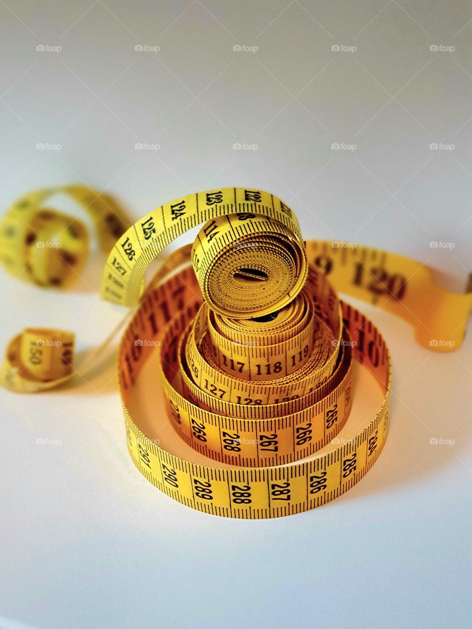 three yellow stacked centimeter measuring tapes, nicely staged