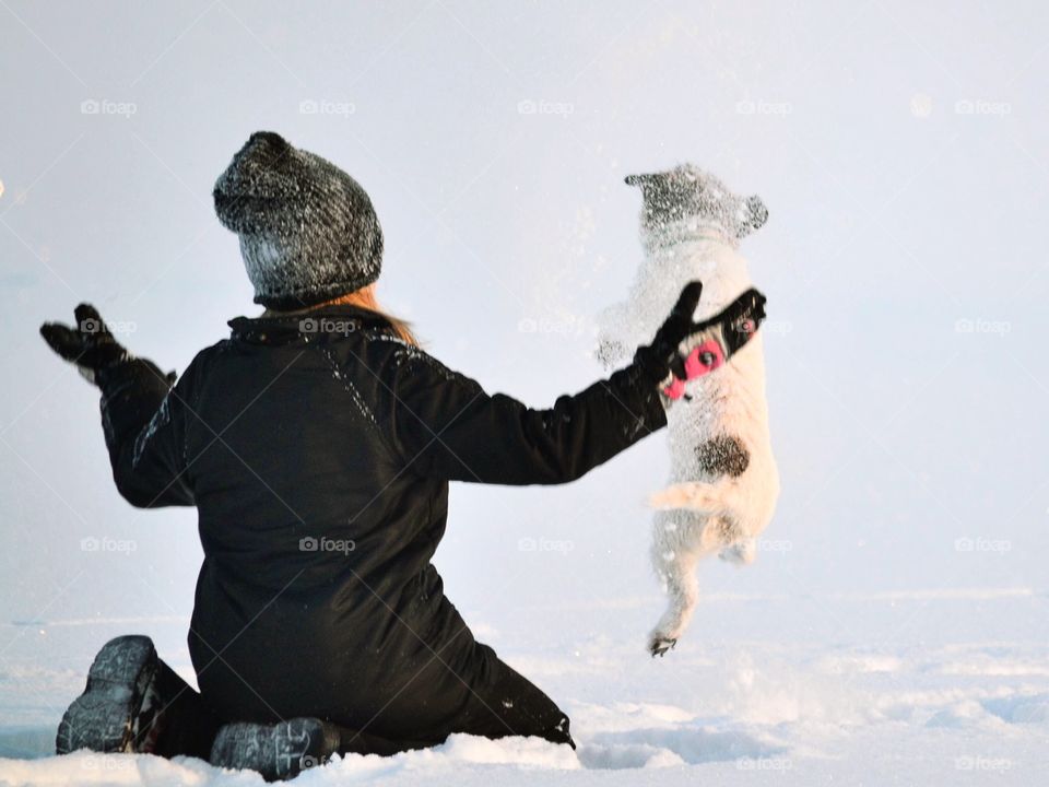 Girl throwing snow and playing with her dog