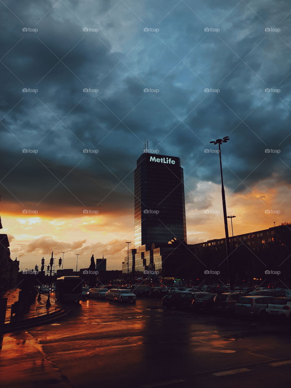 Evening Warsaw cityscape with dramatic stormy clouds and reddish sunset.