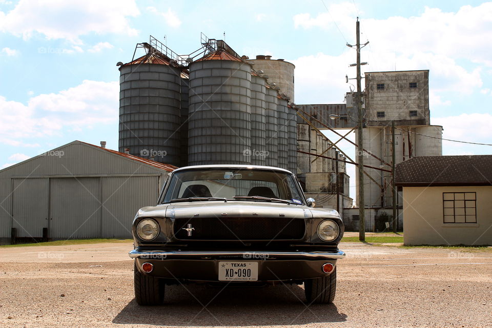 Classic gray 1965 mustang by grain silos. American muscle car