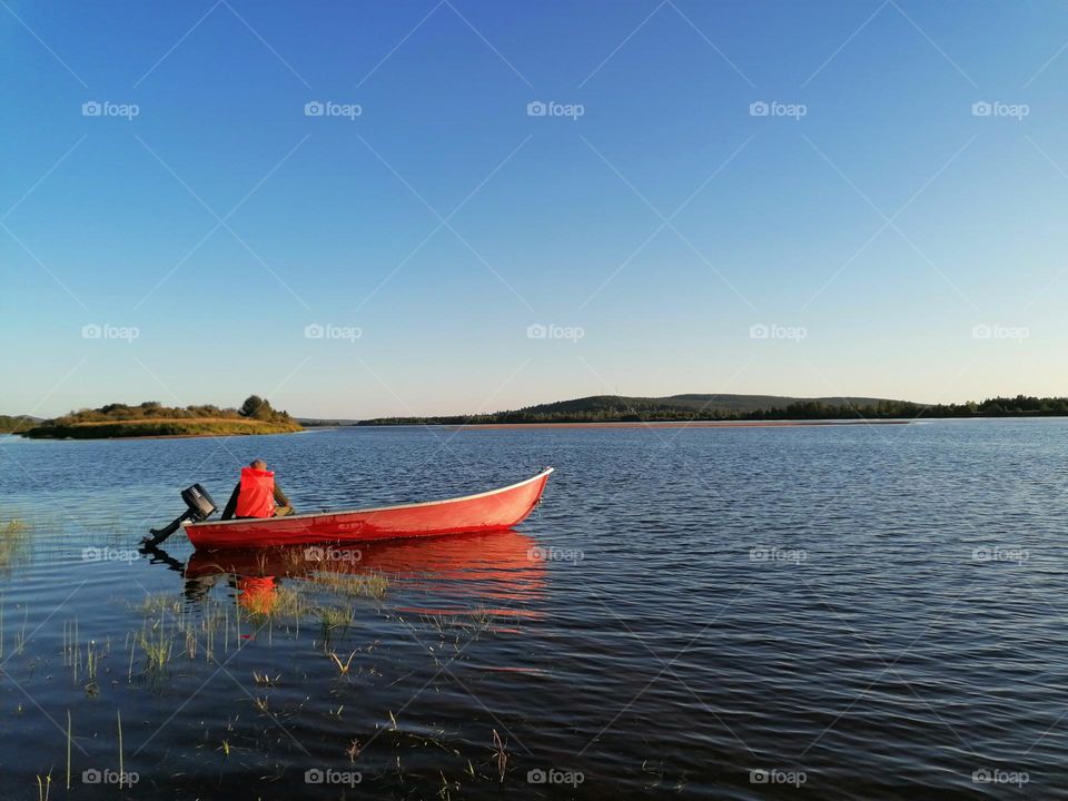 A man in a boat in summer on Tornio river ( Tornionjoki) in Finnish Lapland going fishing