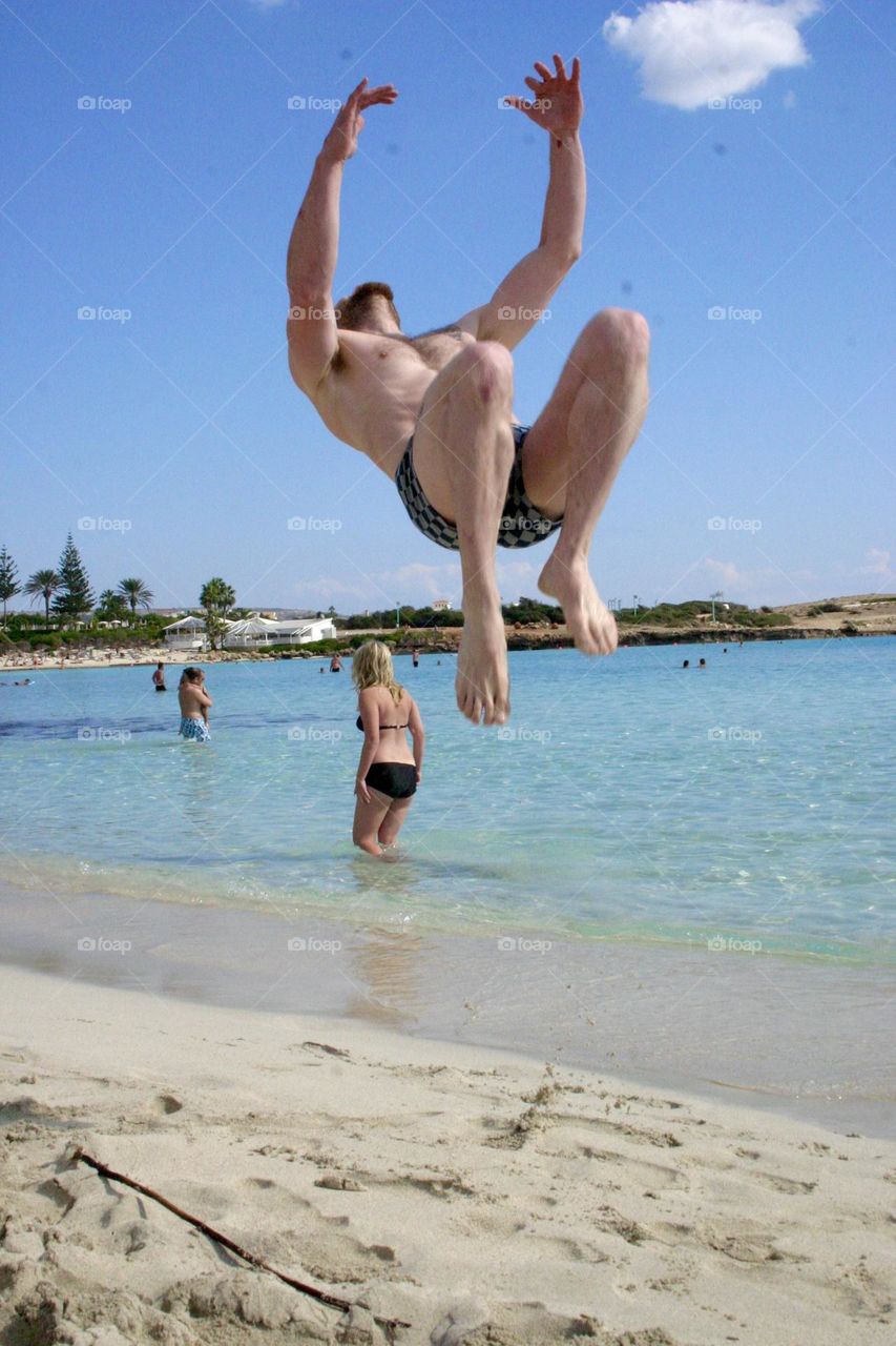 Young man jump for flip on the beach