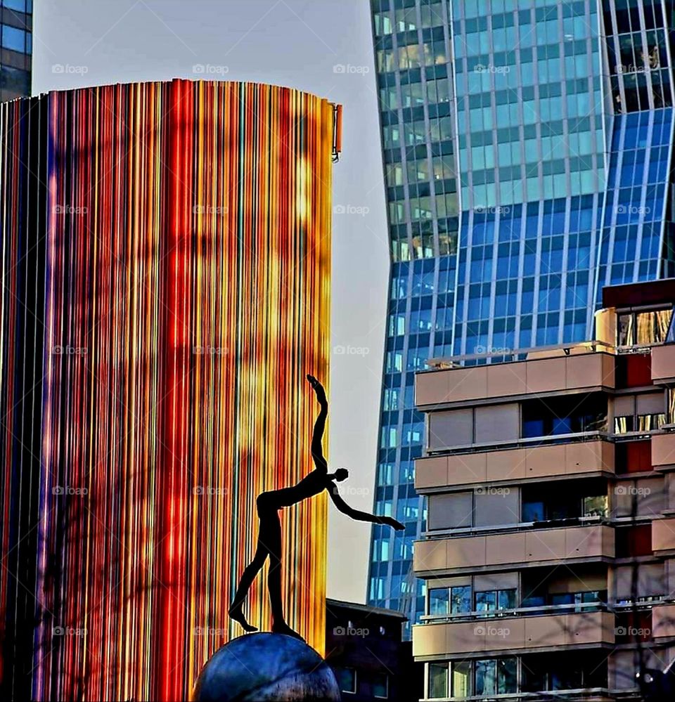 Vibrant multi colours stripes fresco by the artist Raymond Moretti on a ventilation chimney and bronze sculpture the "Somnambule" perched on a sphere by the artist Henri de Miller in the Défense district in Courbevoie, in the suburb of Paris