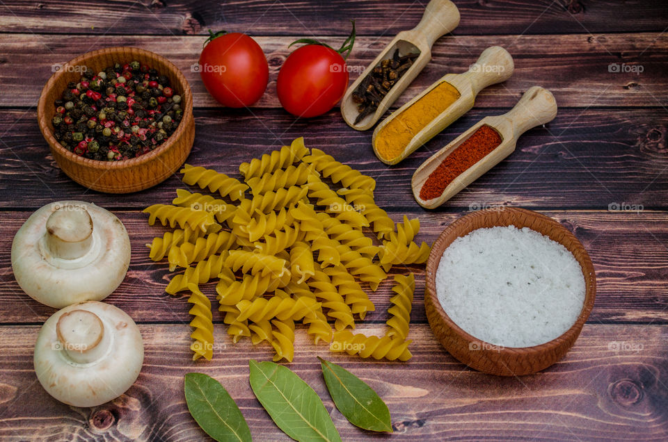 Raw pasta with ingredients and wooden accessories