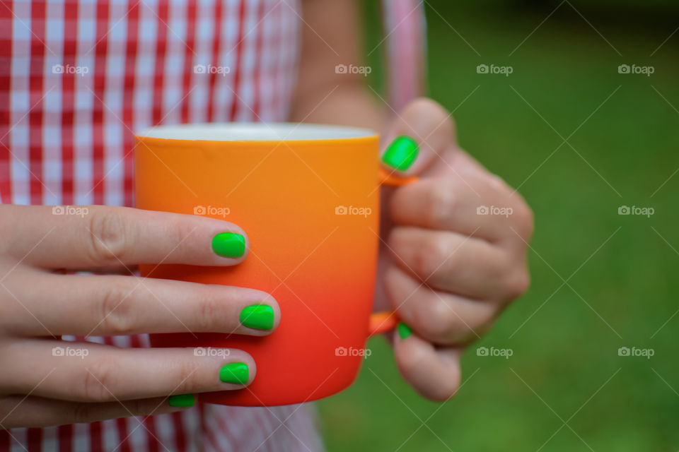 orange cup of tea and green nails