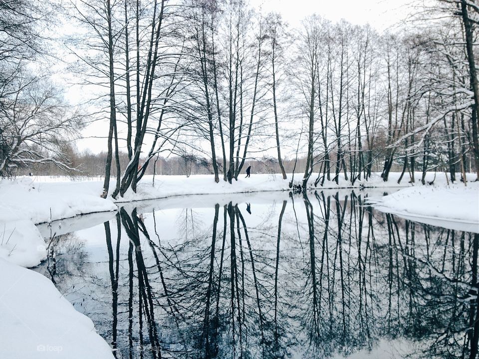 Solitude of men walking near frozen river in winter