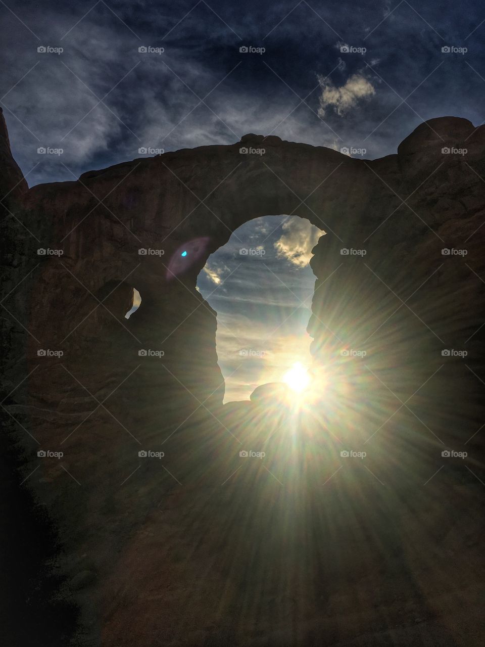 Sun sets behind a stone window at Arches National Park in Utah