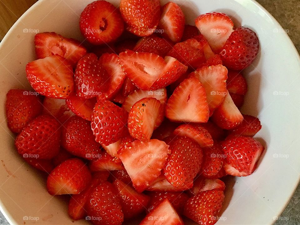 Sliced red strawberries in white bowl still life  closeup 