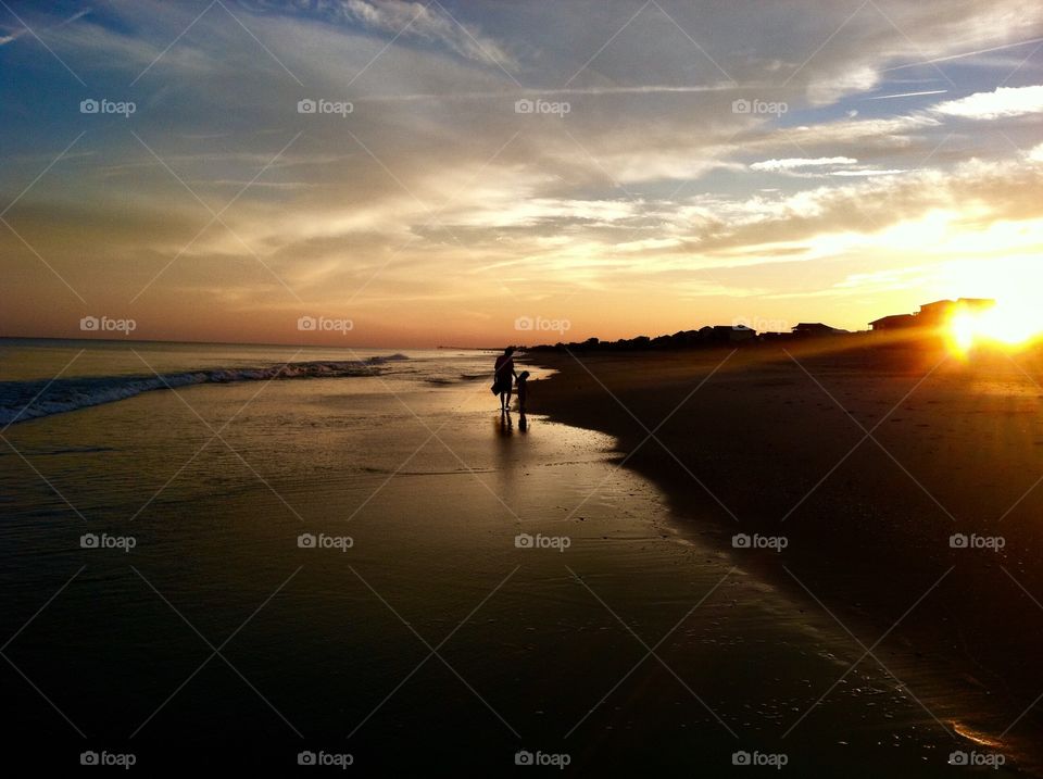 Mother and daughter strolling on the peaceful beach during sunset at Emerald Isle North Carolina 