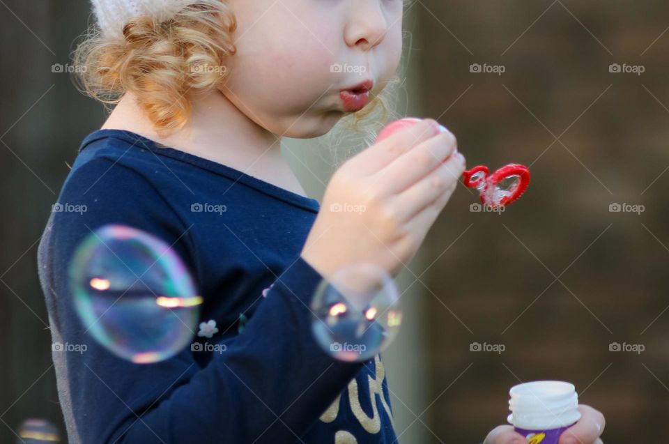 Close up of a toddler blowing bubbles