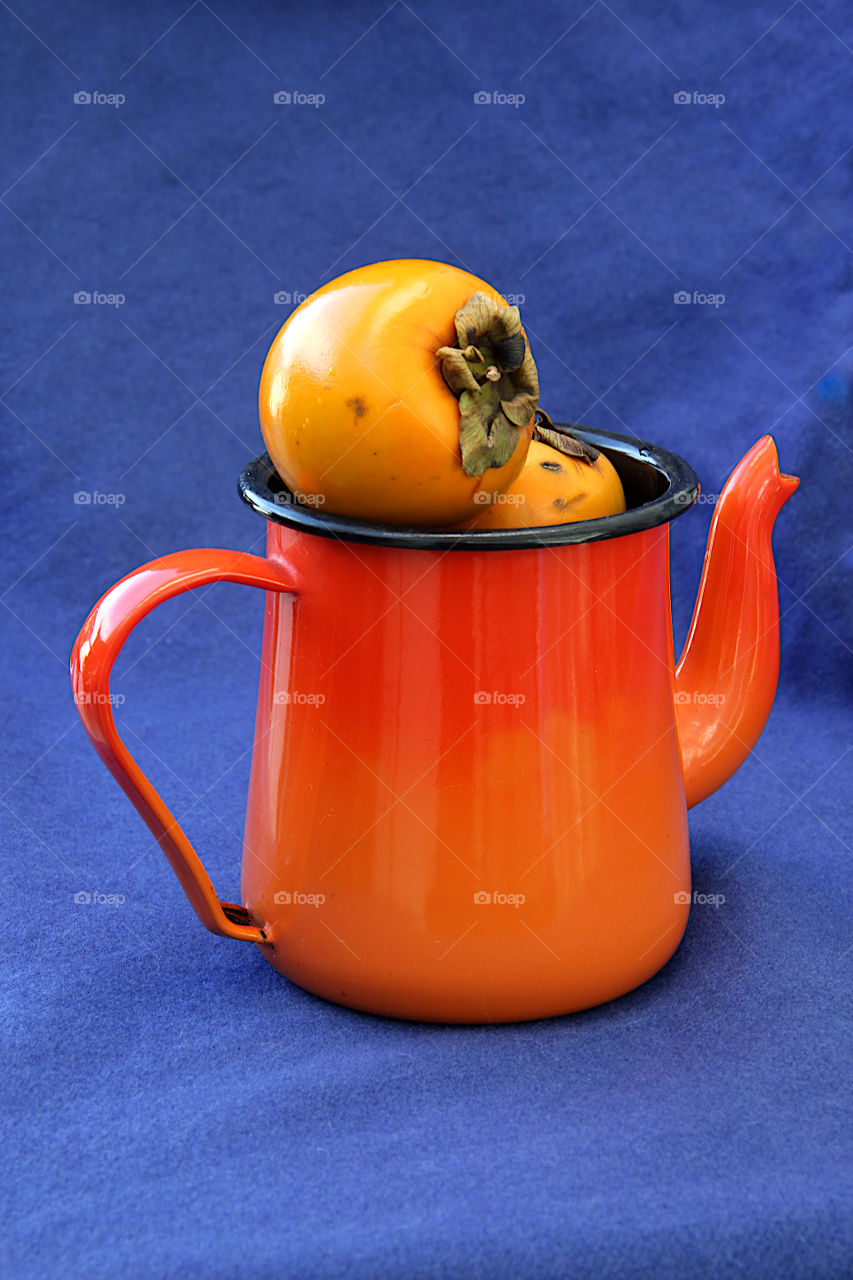 Teapot and persimmon in blue and orange colors