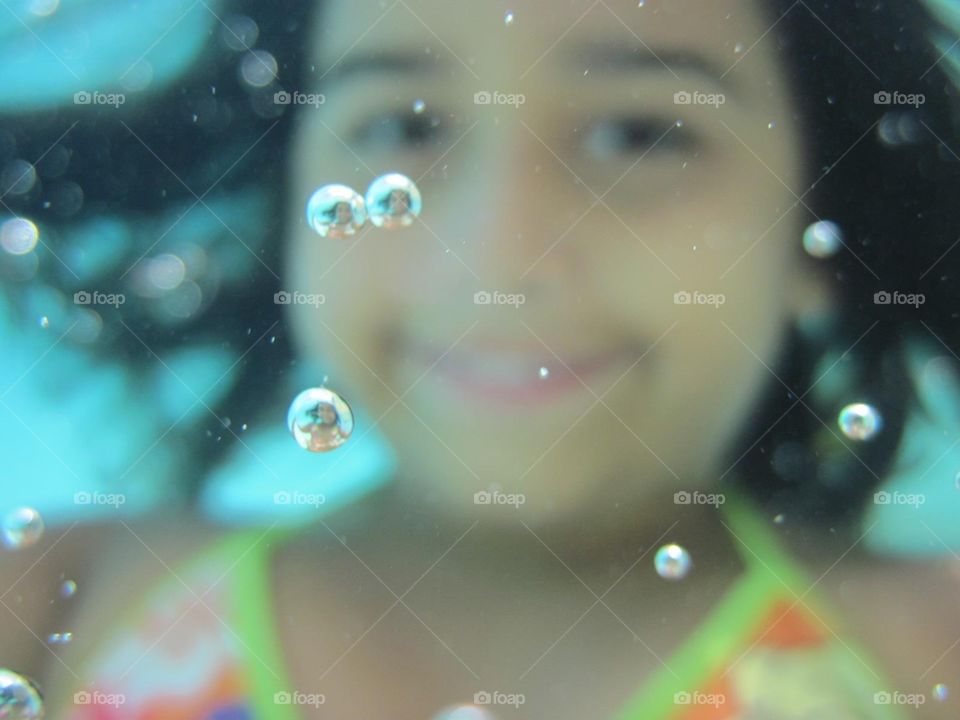 Selfie de uma menina embaixo da água com várias bolhas com reflexo da própria menina 
