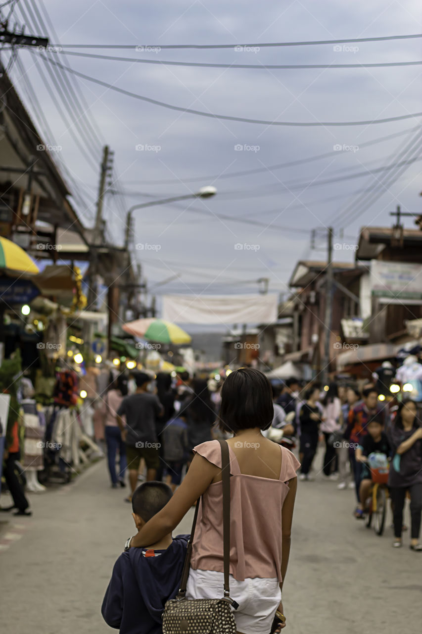 Mother and son on the street and blurry tourists at Walking Street Chiang Khan, Loei in Thailand.