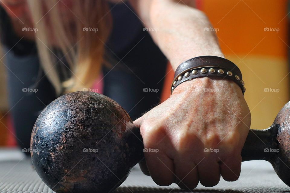Close-up of a woman's hand holding a rusty dumbbell