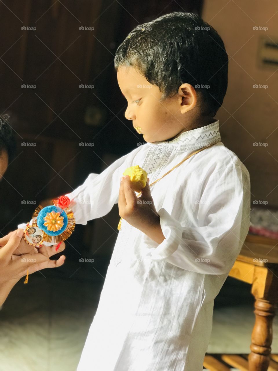 Indian boy wearing traditional dress on rakhi powrnamiand eating sweet.