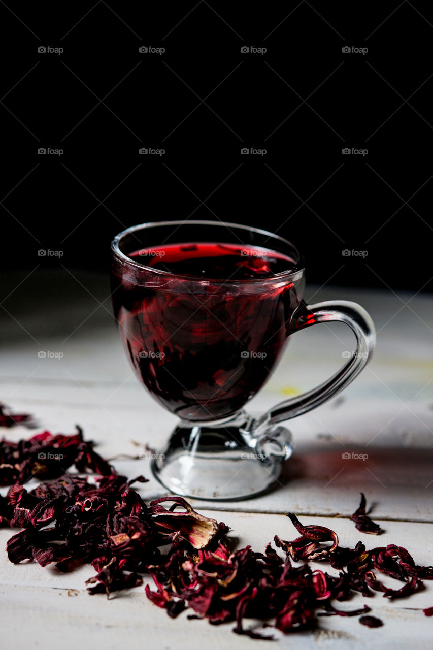 Red hot hibiscus tea in a glass cup on a wooden table