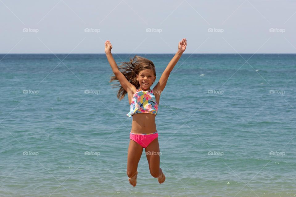 Beautiful happy caucasian child of 7-8 years jumping on sea background