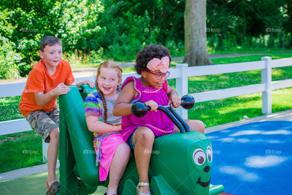 Three Kids at the Playground on the Caterpillar Having Fun