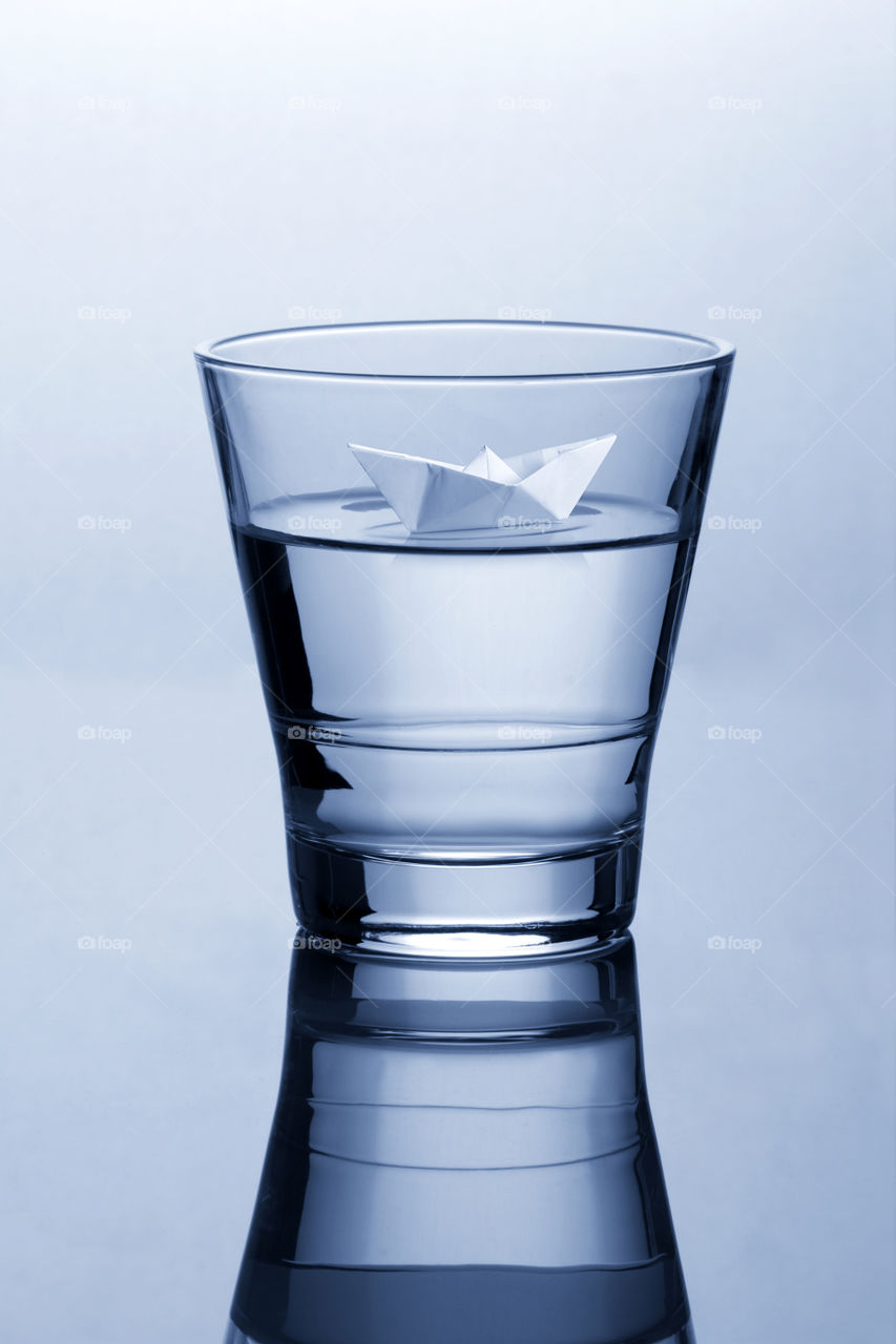 Glass of water with paper origami boat