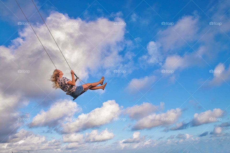 Girl on a swing in the clouds
