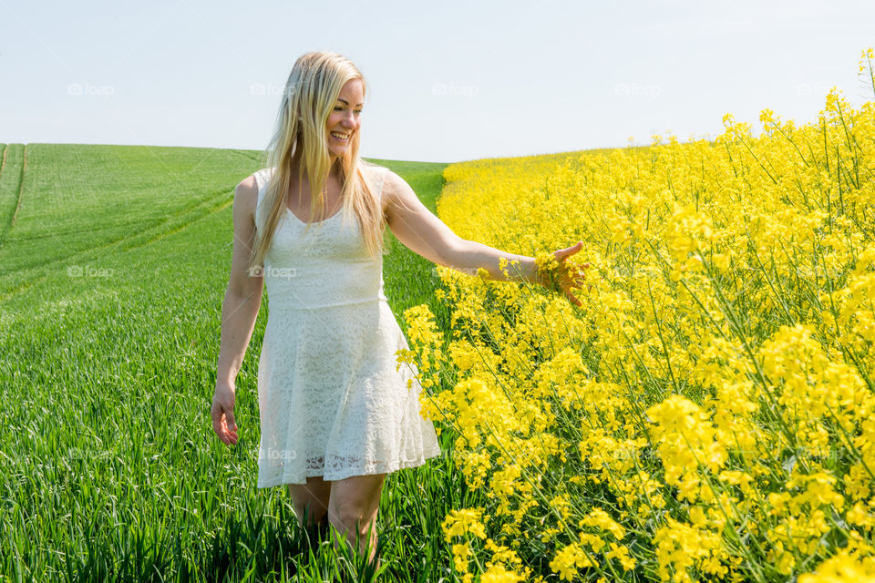 Happy woman touching yellow flower in field