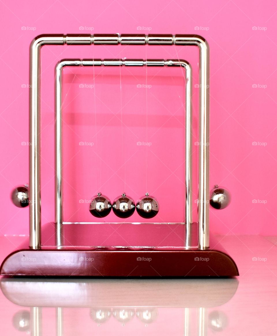 Newton’s cradle with pink background