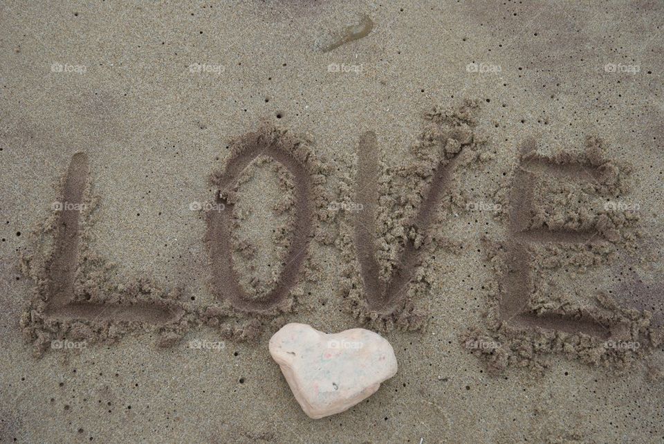 Concept of love on the sand with a stone heart