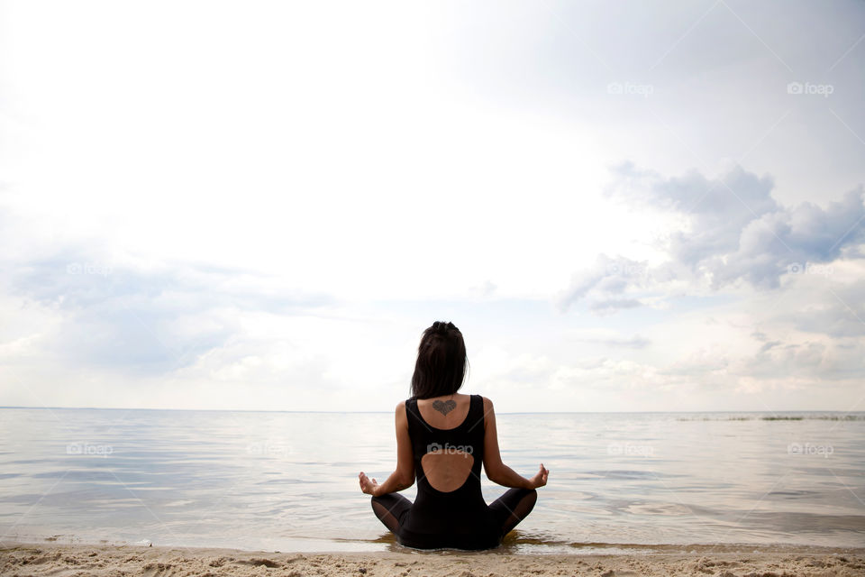 a beautiful girl, during quarantine, sits on the shore of the lake, meditates and thinks about good things.social distance