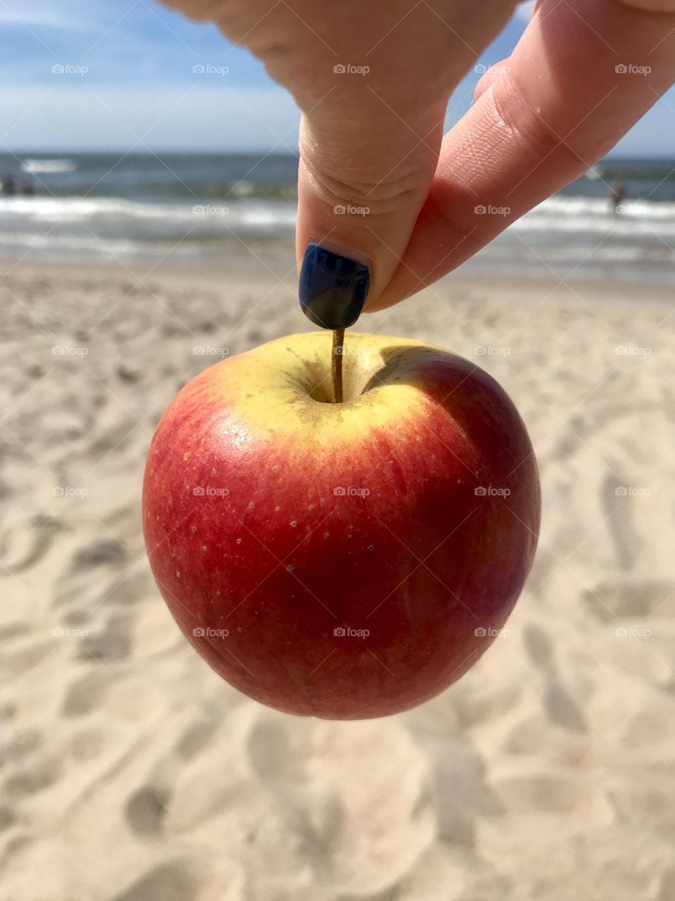 An apple on the hand and sea as a background 