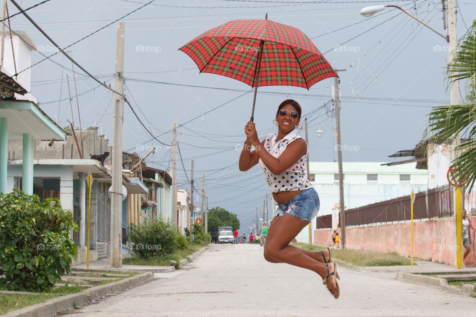 Woman jumping on the road with an umbrella in his hand