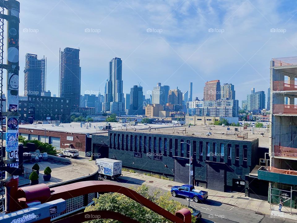 This is a view off the „Pulaski Bridge“ at „Newtown Creek“ on the „Greenpoint“, Brooklyn side of the bridge. Looking past adjacent rooftops we can see „Greenpoint“, LIC, Queens and „Manhattan“. 2023. Hypnotic Productions