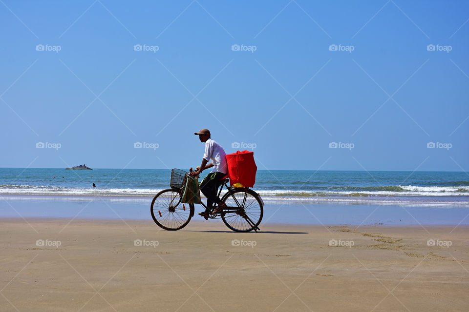 salesman in a cycle on a beach