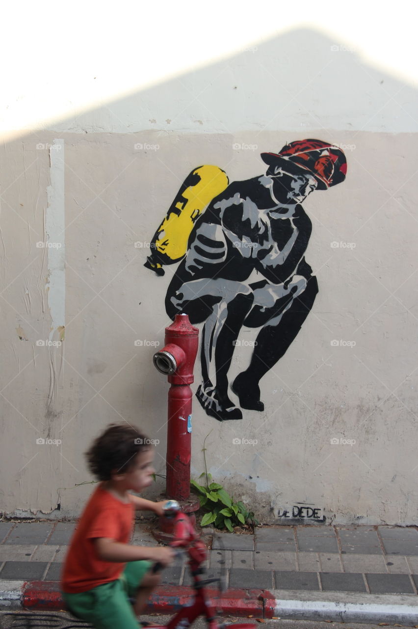 Fast child on bike before mural
