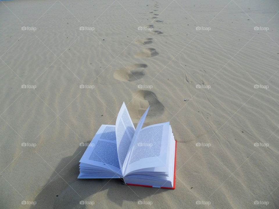 An open book lies on the sand