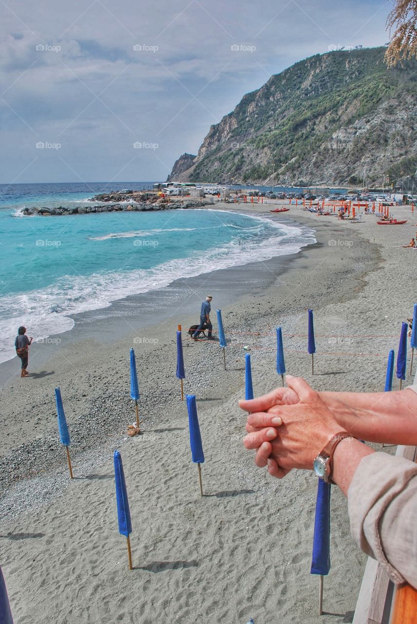 Beach balcony. A traveler's hands rest on a  balcony overlooking a beautiful beach