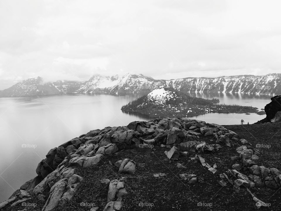 A rocky ledge on the rim overlooking Crater Lake and Wizard Island on a cold day. 