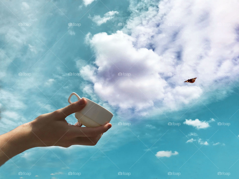 Hand Catching the white clouds into the cup from the blue sky 