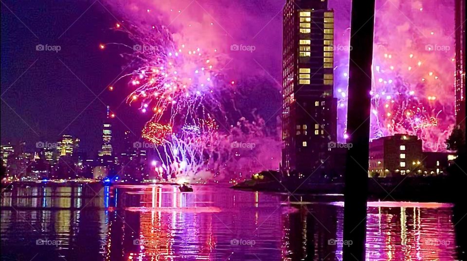 The „July 4th 2022 Macy’s Independence Day fireworks“ are being launched from several boats anchored along NYC‘s „East River“ this year. On the right you can see the silhouetted outlines of LIC high rises. Hypnotic Productions