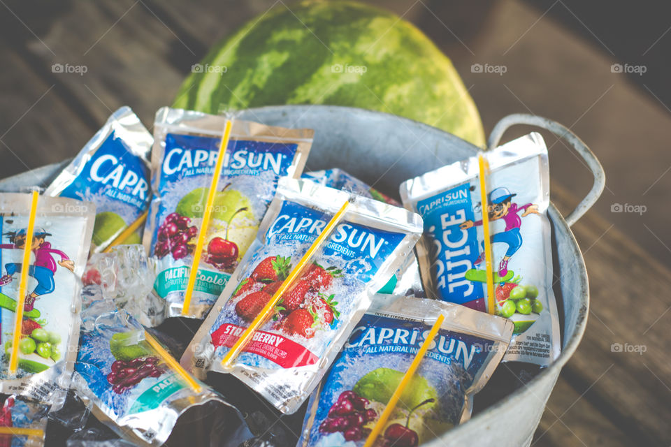 Bucket of Capri Sun Juice Pouches on Ice with Watermelon in Background 2