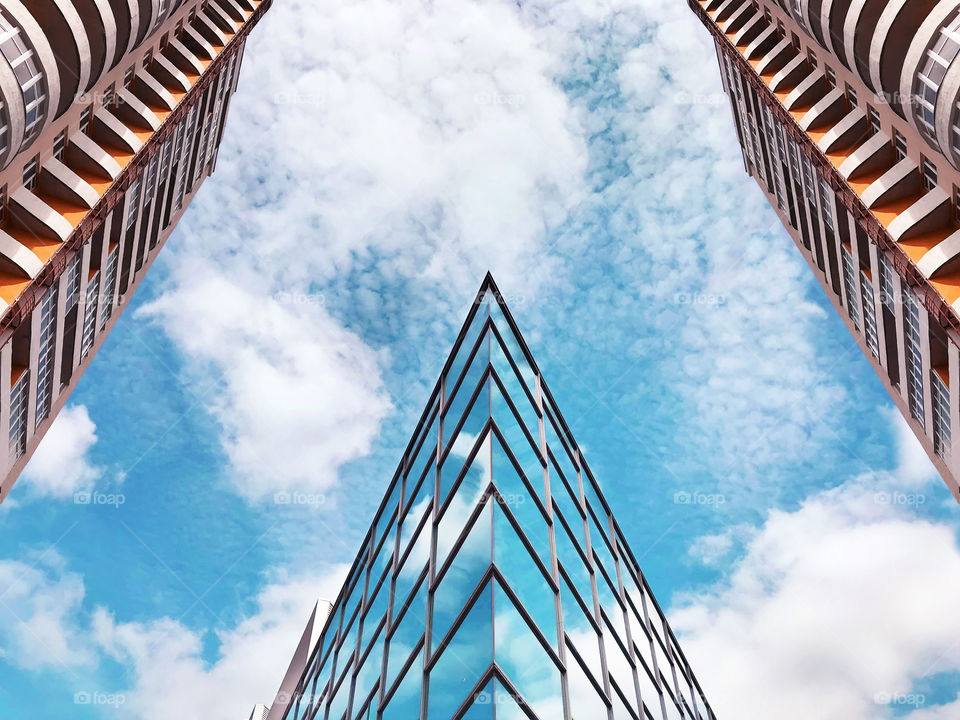 Top view of  modern buildings in the city in front of blue cloudy sky 