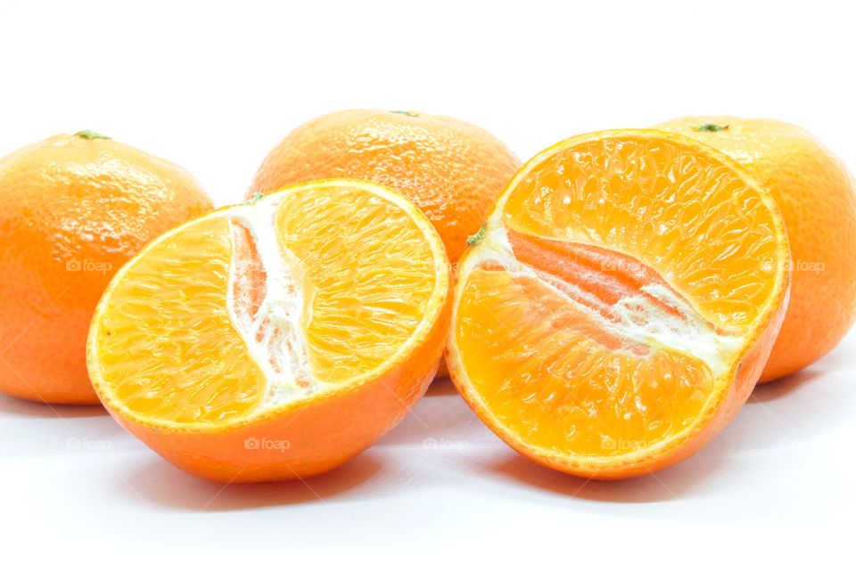Three whole mandarins and one cut on a white background